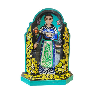 San Pascual wooden altar with an image of San Pascual holding a bowl of food in a kitchen with multicolored filgree borders.