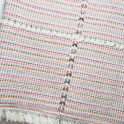 close up of natural multi-colored striped handwoven napkin folded in quarters. Thin stripes consist of the following colors: red, tan, light blue, black, beige