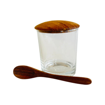 Mini glass cellar with teak lid and wooden spoon shown outside of jar.