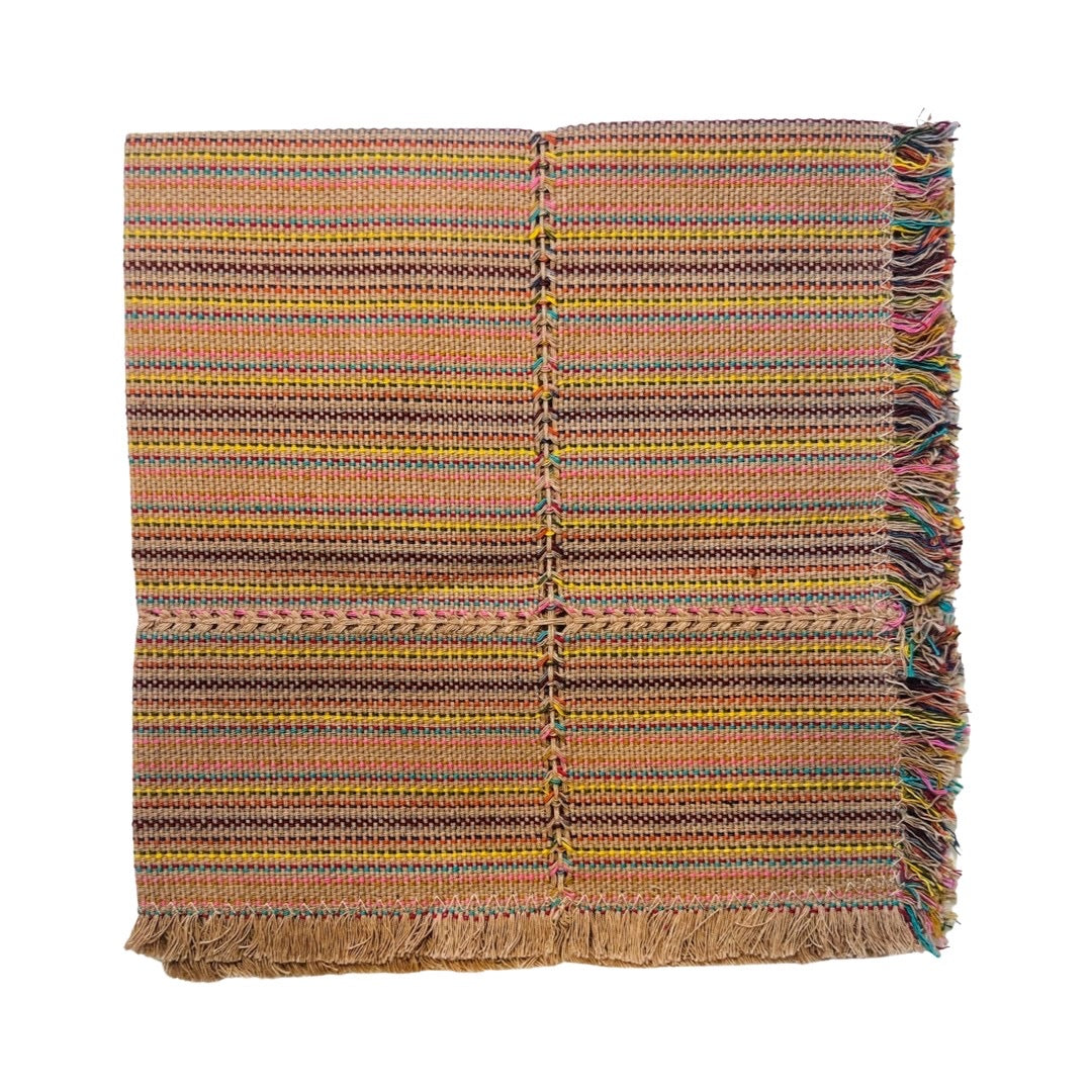 Handwoven cotton napkin folded in quarters and features stripes in the color yellow, red, turquoise, pink and clay.