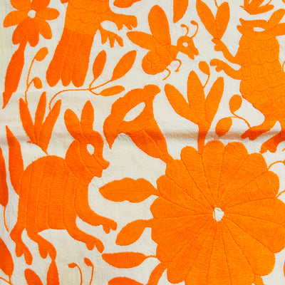 enhanced view of orange floral and fauna scenery detail embroidered on off white table runner