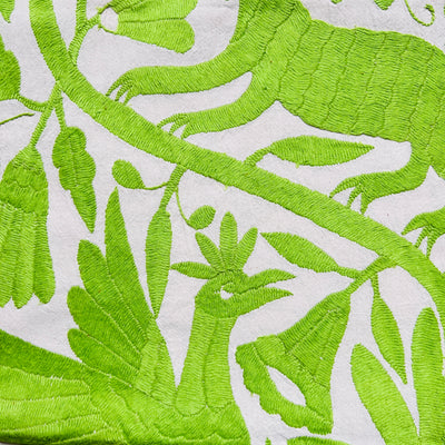 enhanced view of green floral and fauna scenery detail embroidered on off white table runner