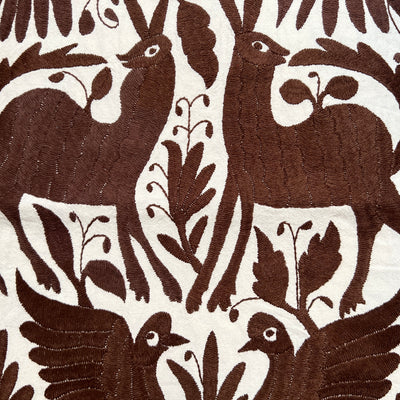 enhanced view of brown floral and fauna scenery detail embroidered on off white table runner