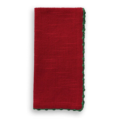 Folded scarlet red cotton napkin with green hand-knotted trim detail along the edge