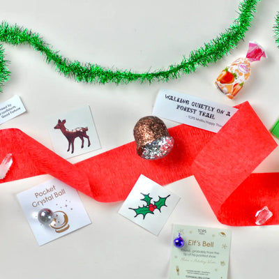 Assorted Christmas-themed items including a red ribbon, crystal ball, and cards on a white background with green tinsel.