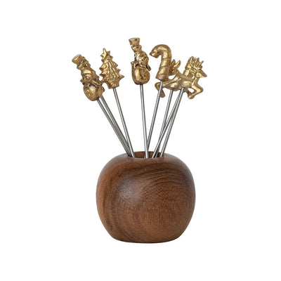 Mango wood holder filled with metal appetizer picks topped with small gold holiday shapes including a snowman, tree, gift, candy cane, and reindeer.