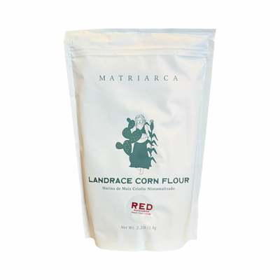 2.2lbs White resealable pouch labeled “Matriarca Landrace Red/Rojo Corn Flour,” featuring a green illustration of a woman with corn and a cactus.