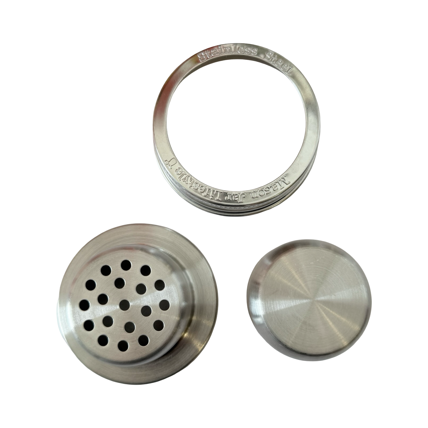 Close-up of a stainless steel mason jar cocktail shaker lid set, including a strainer insert, cap, and screw band marked with "Stainless Steel" engraving.
