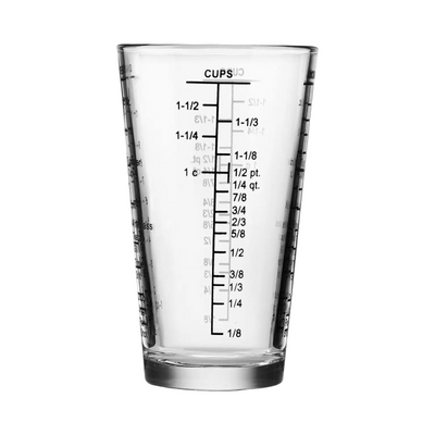 Clear pint-sized measuring glass with black printed measurements in cups, ounces, pints, and quarts.