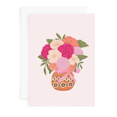 Floral arrangement in a decorative vase on a light pink background