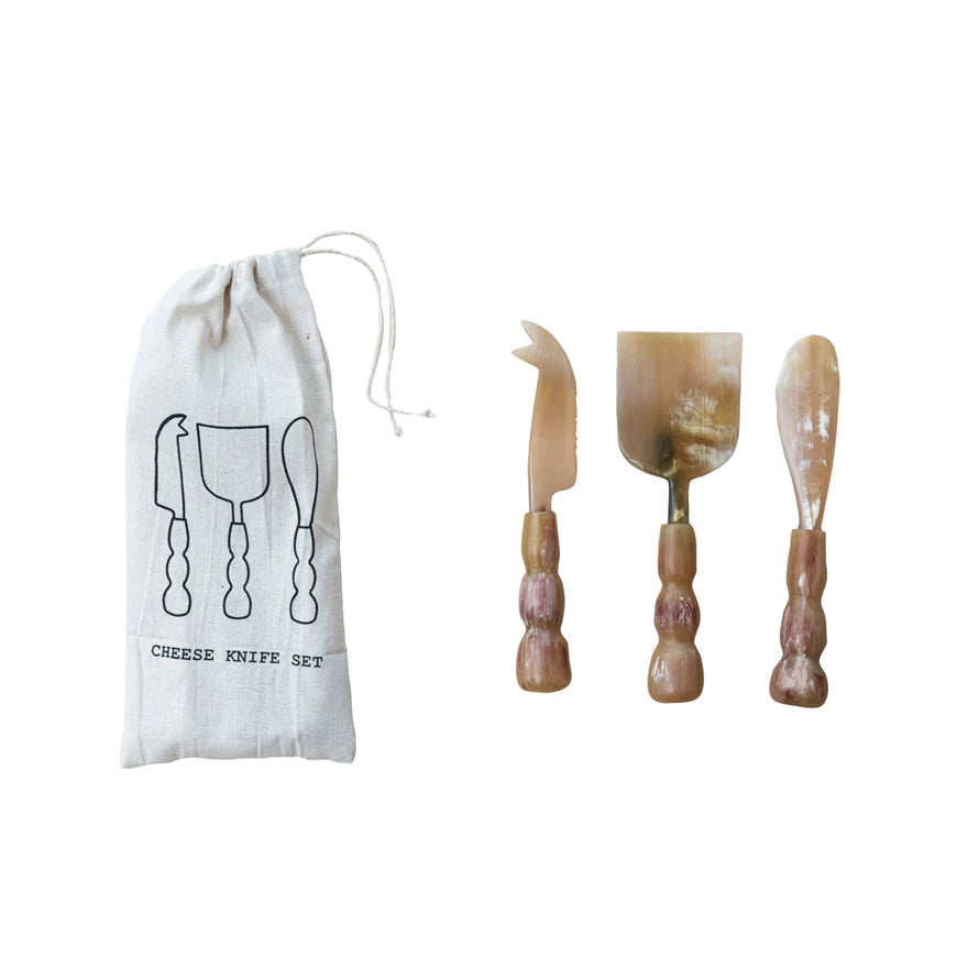 Set of three natural horn cheese servers with sculpted handles, shown with a linen drawstring bag labeled “Cheese Knife Set.”