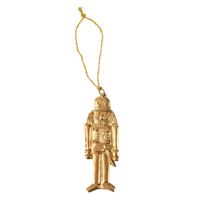 Gold-toned metal nutcracker milagro ornament with embossed details and a gold hanging string.