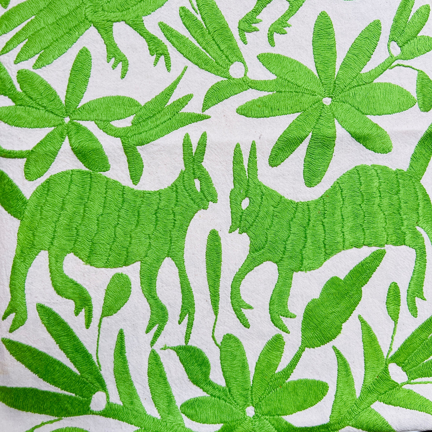 enhanced view of green floral and fauna scenery detail embroidered on off white table runner
