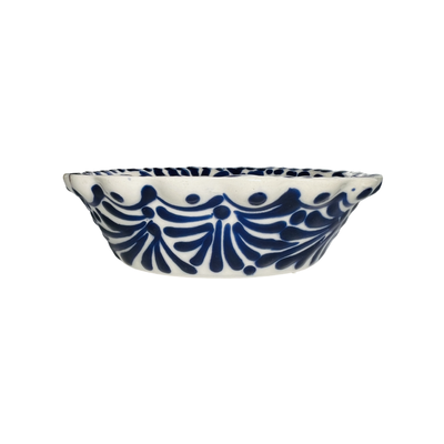 A handcrafted ceramic bowl with blue and white scalloped rim and geometric patterns, isolated on a white background.