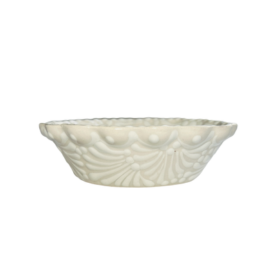 A handcrafted ceramic bowl with a scalloped rim and a cream and white glazed design.