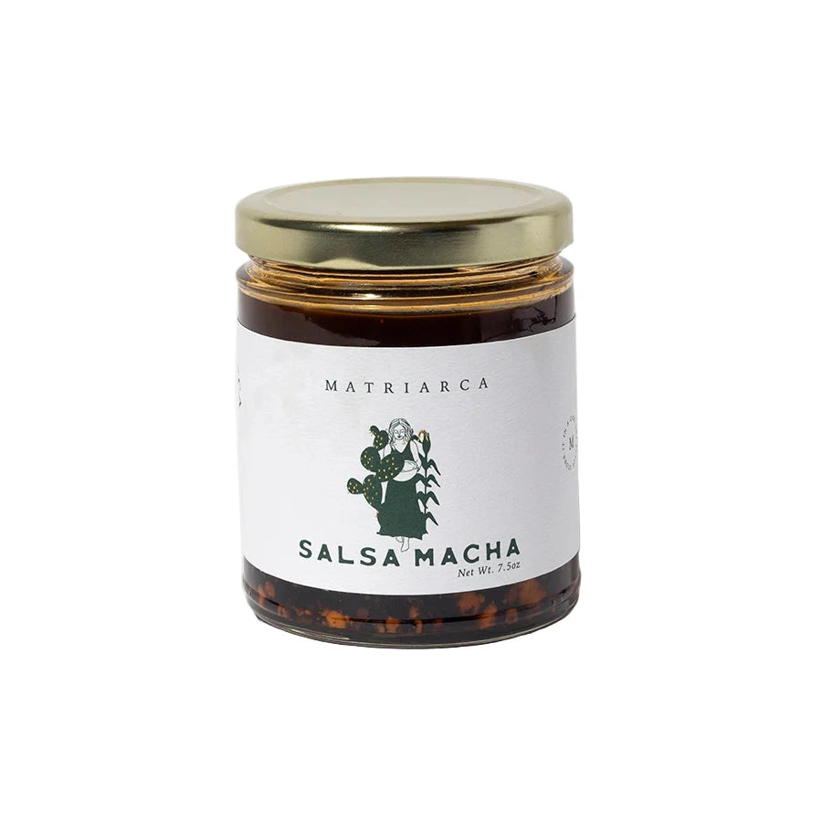 7. oz Glass jar labeled “Salsa Macha” by Matriarca, filled with dark red chile oil and visible pistachio and chile pieces, with a gold lid.