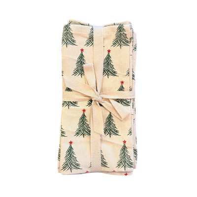 Set of four stonewashed cotton napkins printed with green Christmas trees topped with red stars, tied together with a beige ribbon.