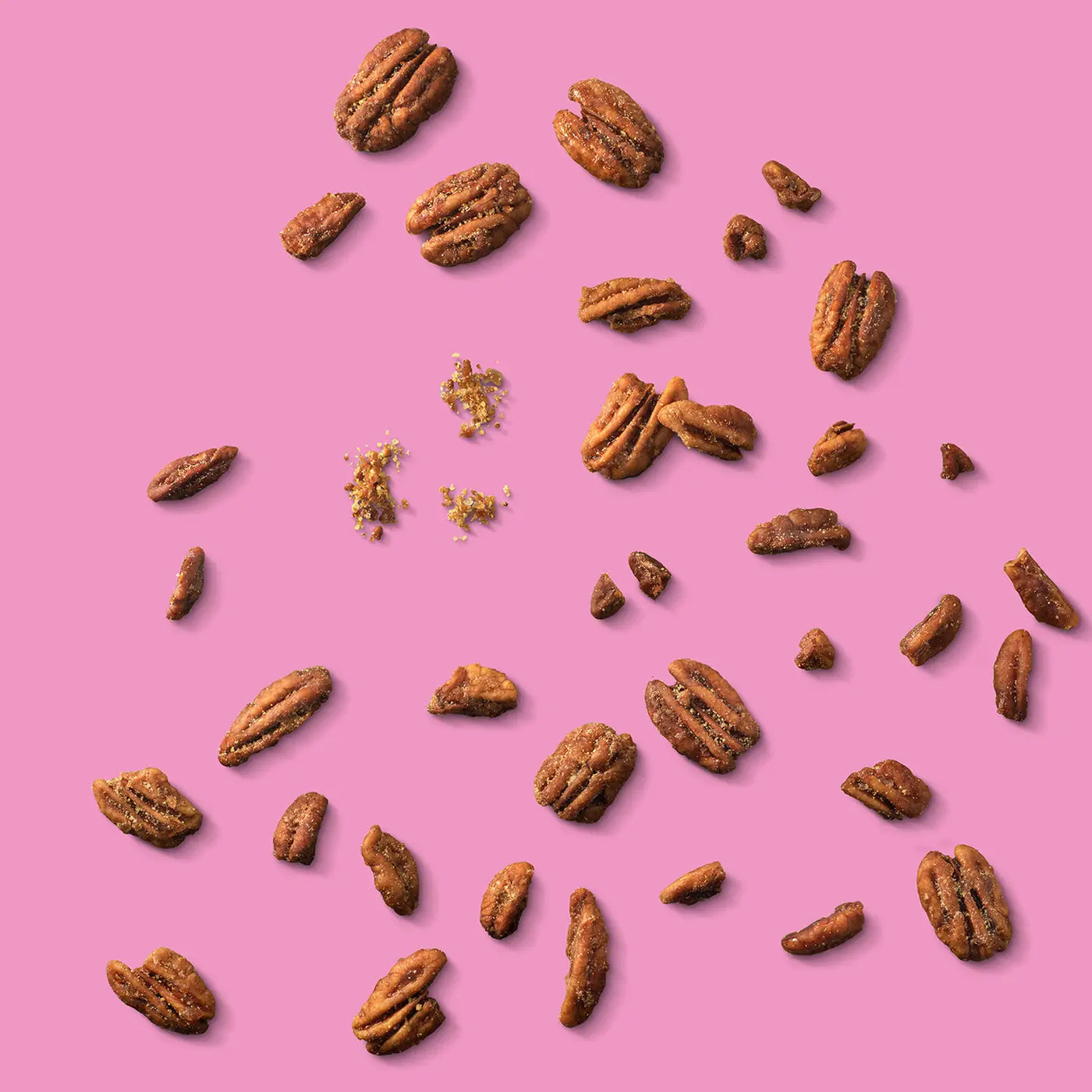 Pecans scattered on a pink background