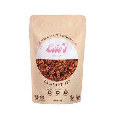 A beige resealable bag of Evie’s Snacks Churro Pecans, featuring a clear window showing the roasted pecans inside. The packaging highlights key features like "Vegan," "Gluten-Free," "Farm Direct," and "Only 4g Added Sugar," with a pink logo and the tagline "Crunchy, Sweet, & Snackable.