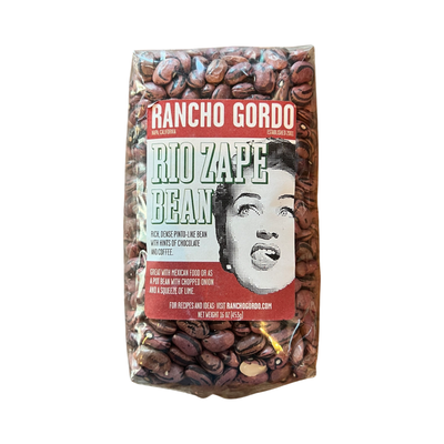 16 oz clear bag of Rio Zape Bean with a white and maroon branded label featuring an image of a woman licking her lips.