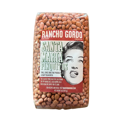 16 oz clear bag of Santa Maria Pinquitos with a white and maroon branded label featuring an image of a woman licking her lips.