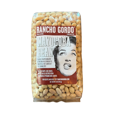 16 oz clear bag of mayocoba bean with a white and maroon branded label featuring an image of a woman licking her lips.