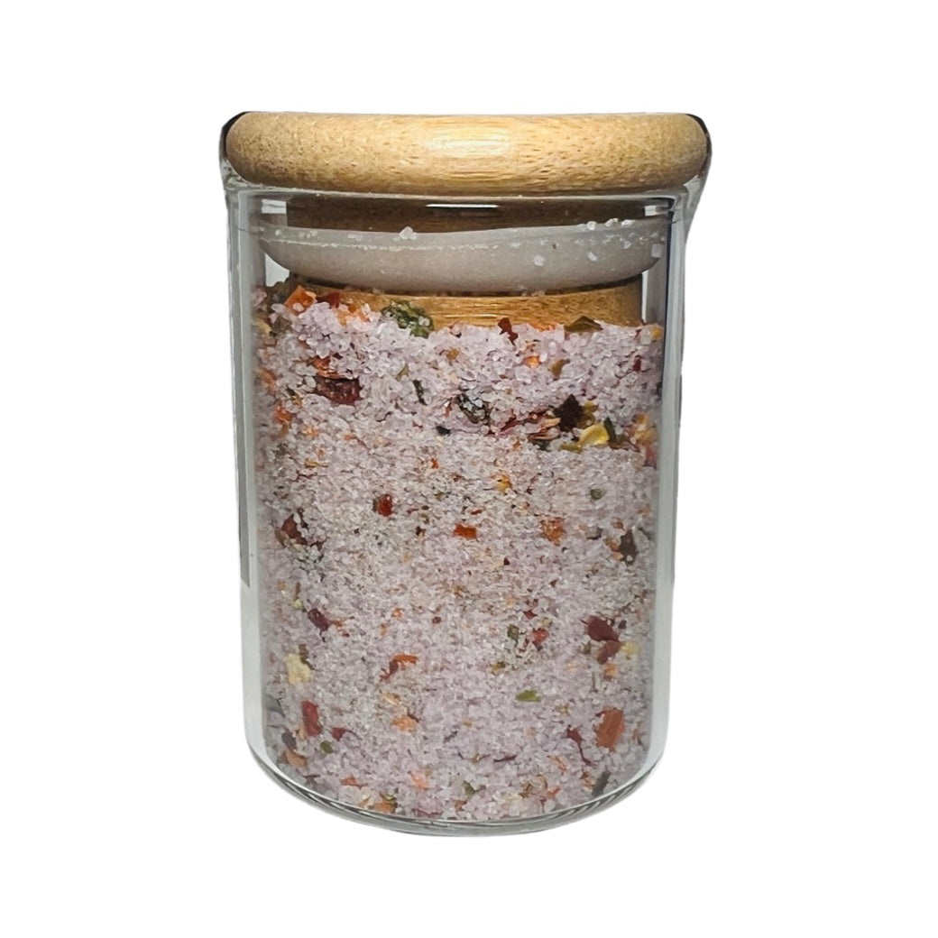 2 oz clear jar of salt with various herbs and fruit and features a wooden lid