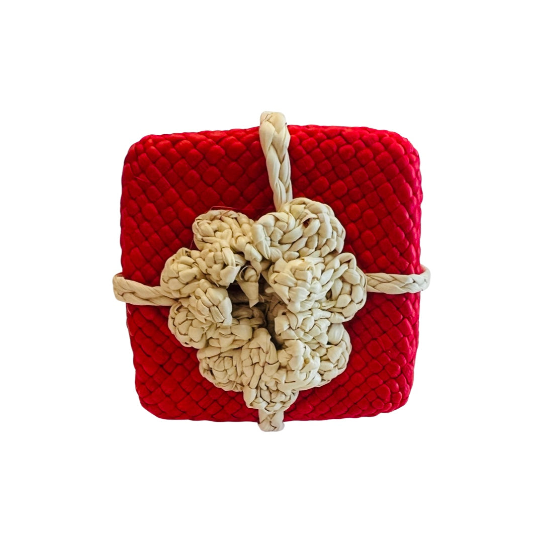 A woven napkin ring designed as a festive Christmas gift, featuring a red box with a braided natural fiber bow, perfect for adding a holiday touch to your table decor.