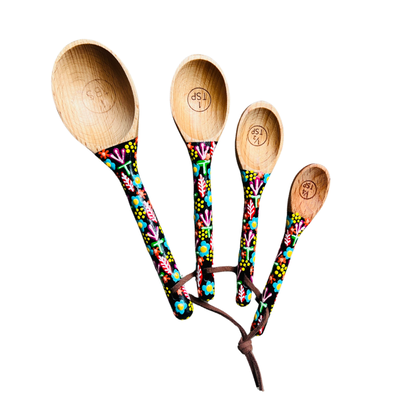 wooden measuring spoons with black painted handles that feature a colorful floral design