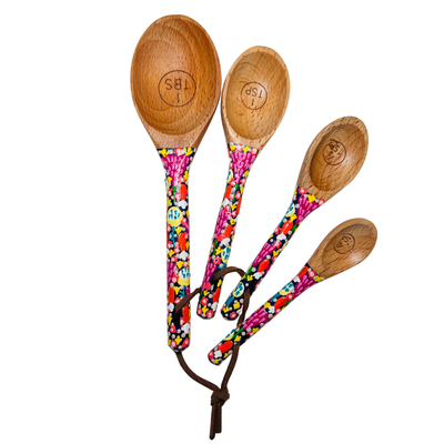 A set of 4 measuring spoons. The set includes 1 tablespoon, 1 teaspoon, 1/2 teaspoon and 1/4 teaspoon.  each handle is painted with a multi-colored floral design.