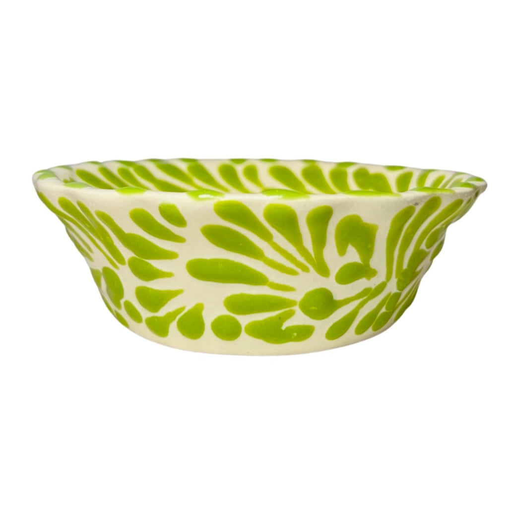 side view of a green and white Puebla design ceramic bowl with a scalloped edge