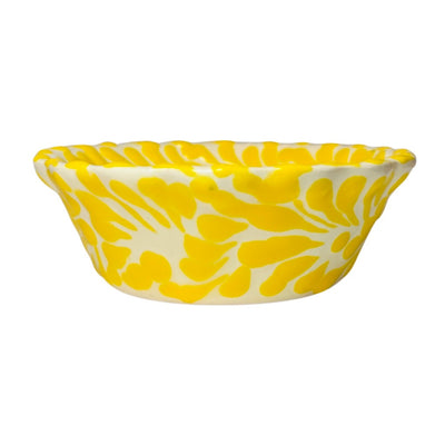 side view of a yellow and white Puebla design ceramic bowl with a scalloped edge