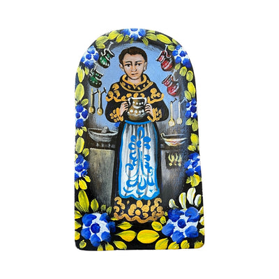 San Pascual retablo featuring an image of San Pascual holding a pitcher in a kitchen with the image bordered with multi-colored flowers and filagree