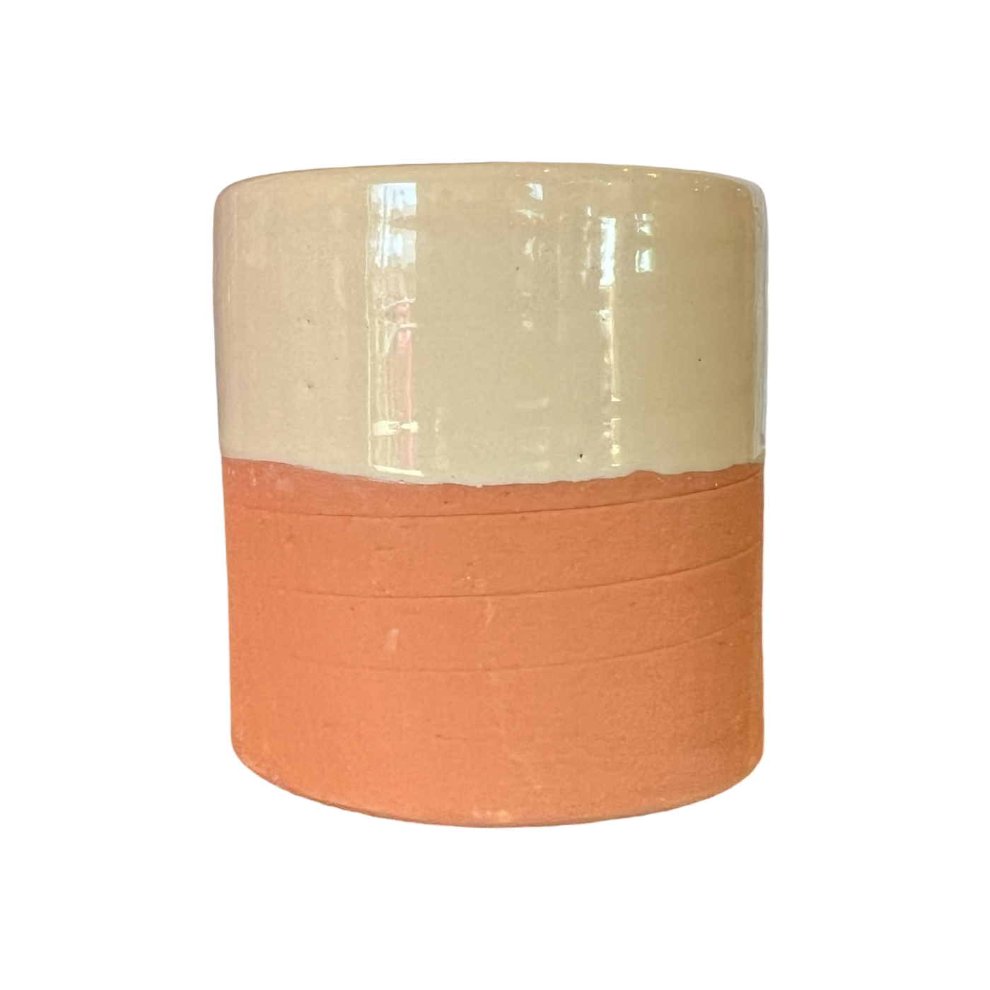 A handcrafted terracotta cup with a cream-colored glazed upper half and an unglazed earthy terracotta base.