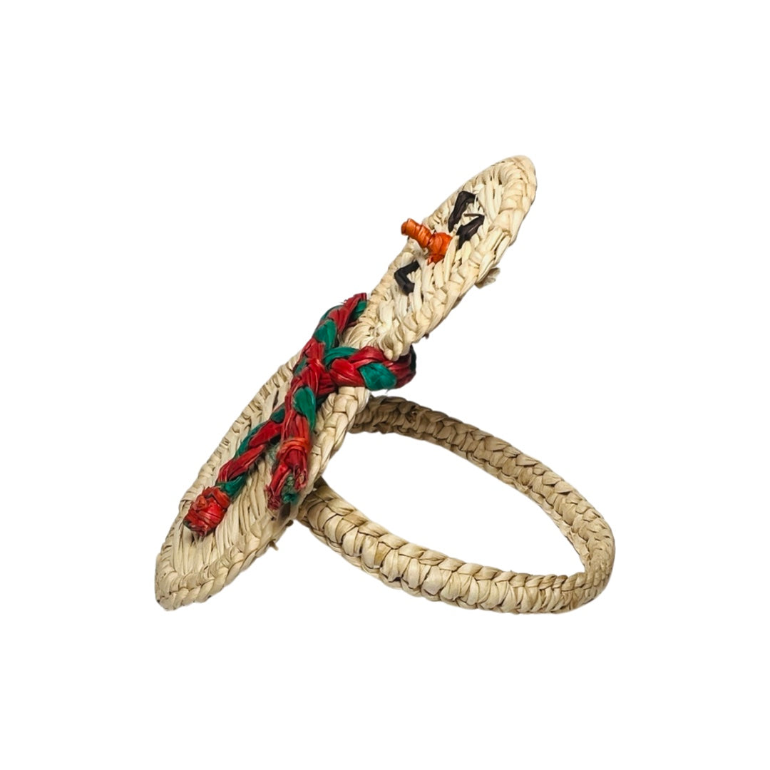 side view of a handcrafted snowman napkin ring made from woven natural fibers, featuring a cheerful face, black button accents, and a braided red and green scarf for a festive touch.