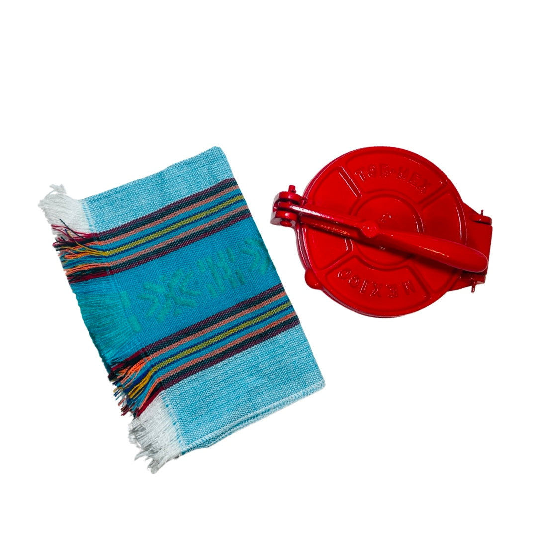Red cast iron tortilla press with a bright baby blue Mexican napkin
