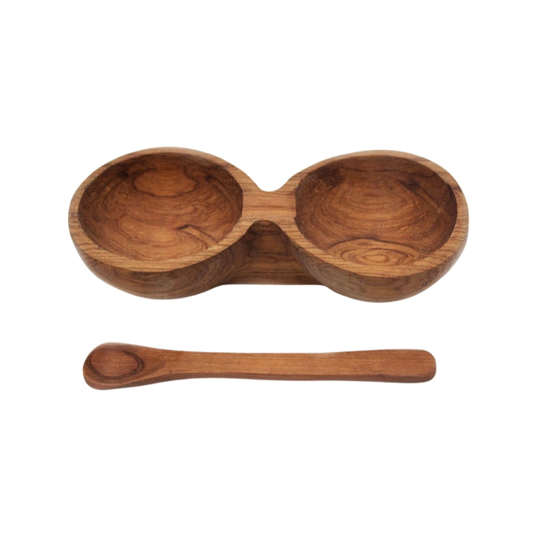 Wooden double bowl with a spoon resting in front of it.