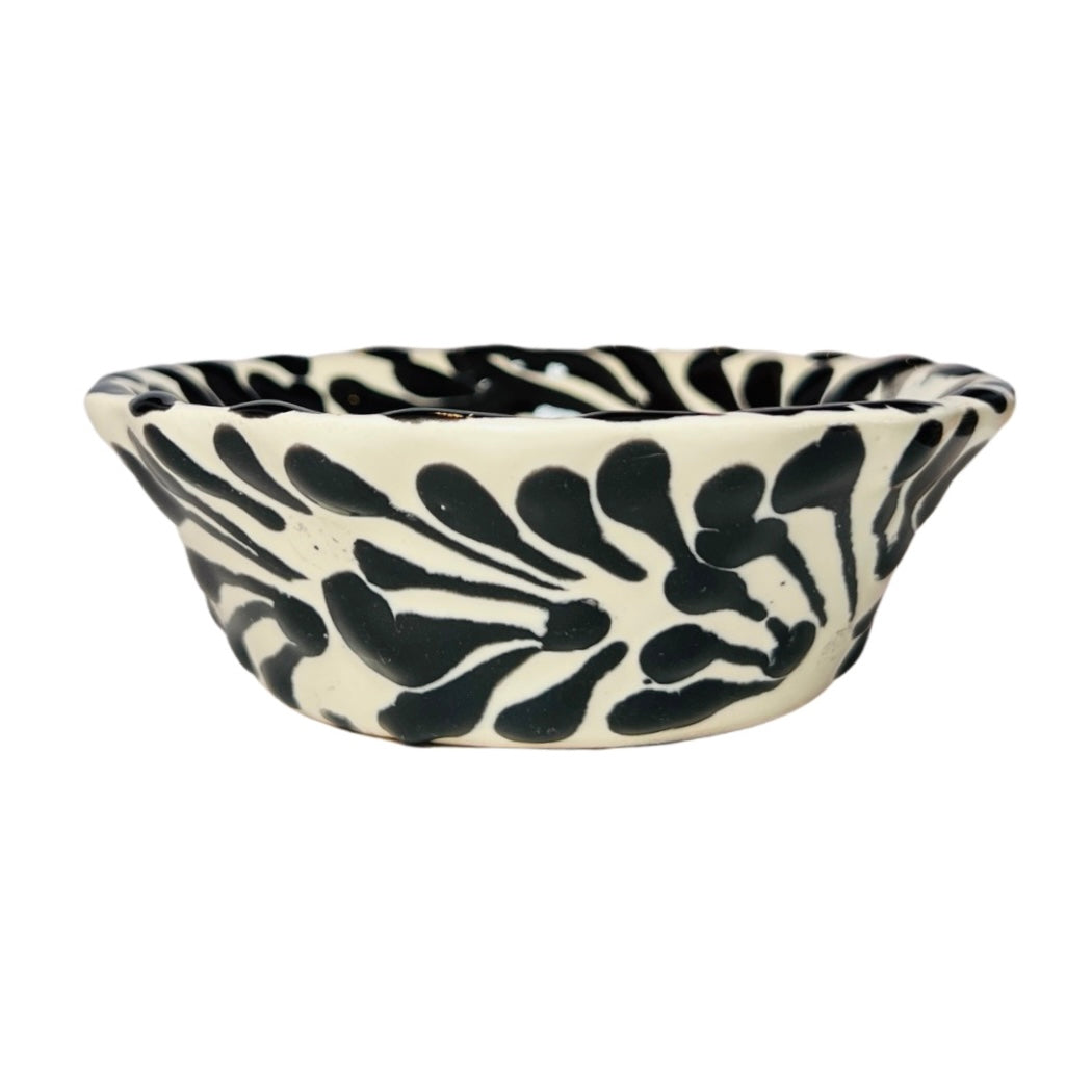 side view of a black and white Puebla design ceramic bowl with a scalloped edge
