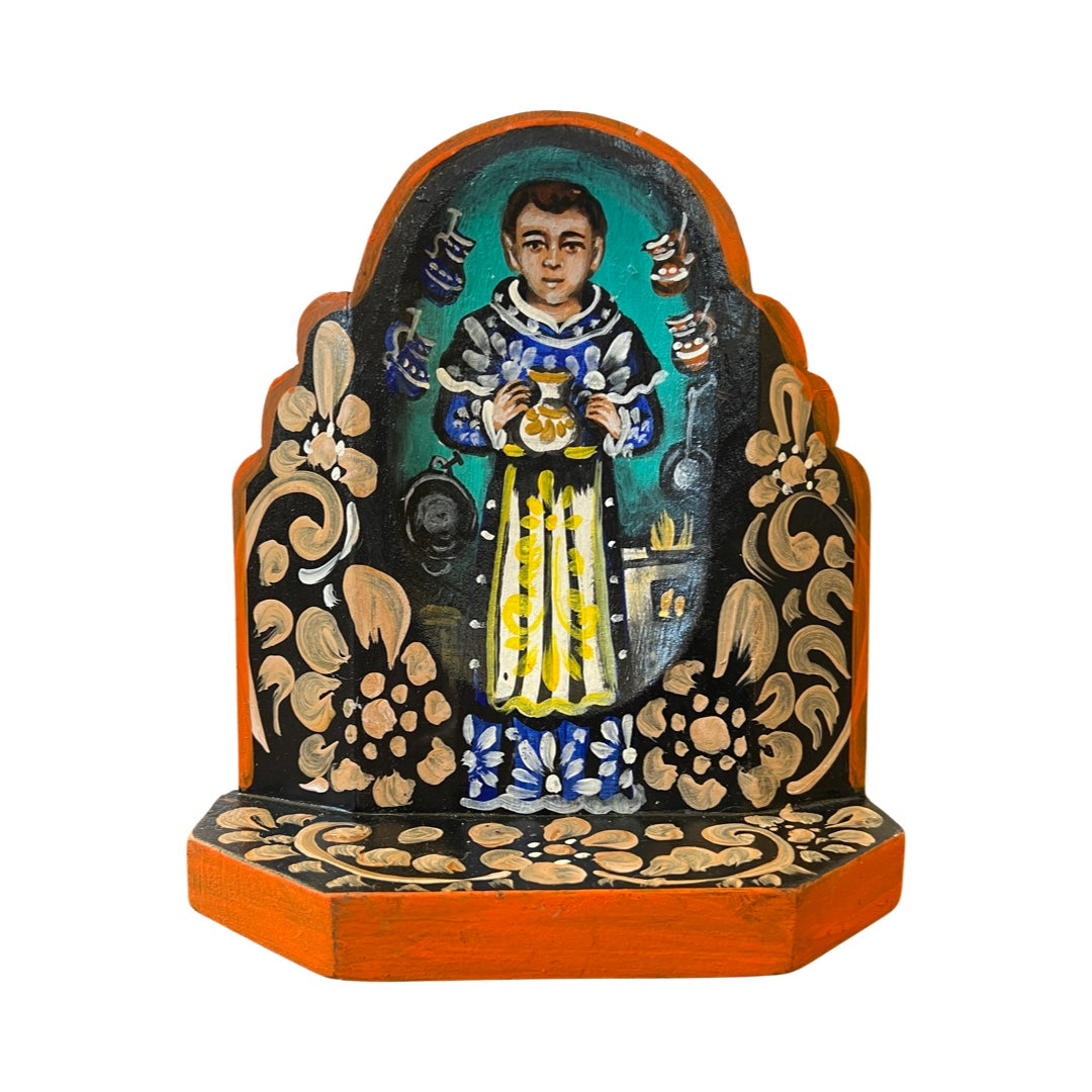 San Pascual wooden altar with an image of San Pascual holding a pitcher in a kitchen with multicolored filgree borders.