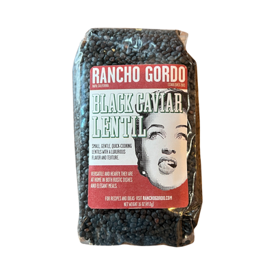 16 oz clear bag of black caviar lentil with a white and maroon branded label featuring an image of a woman licking her lips.
