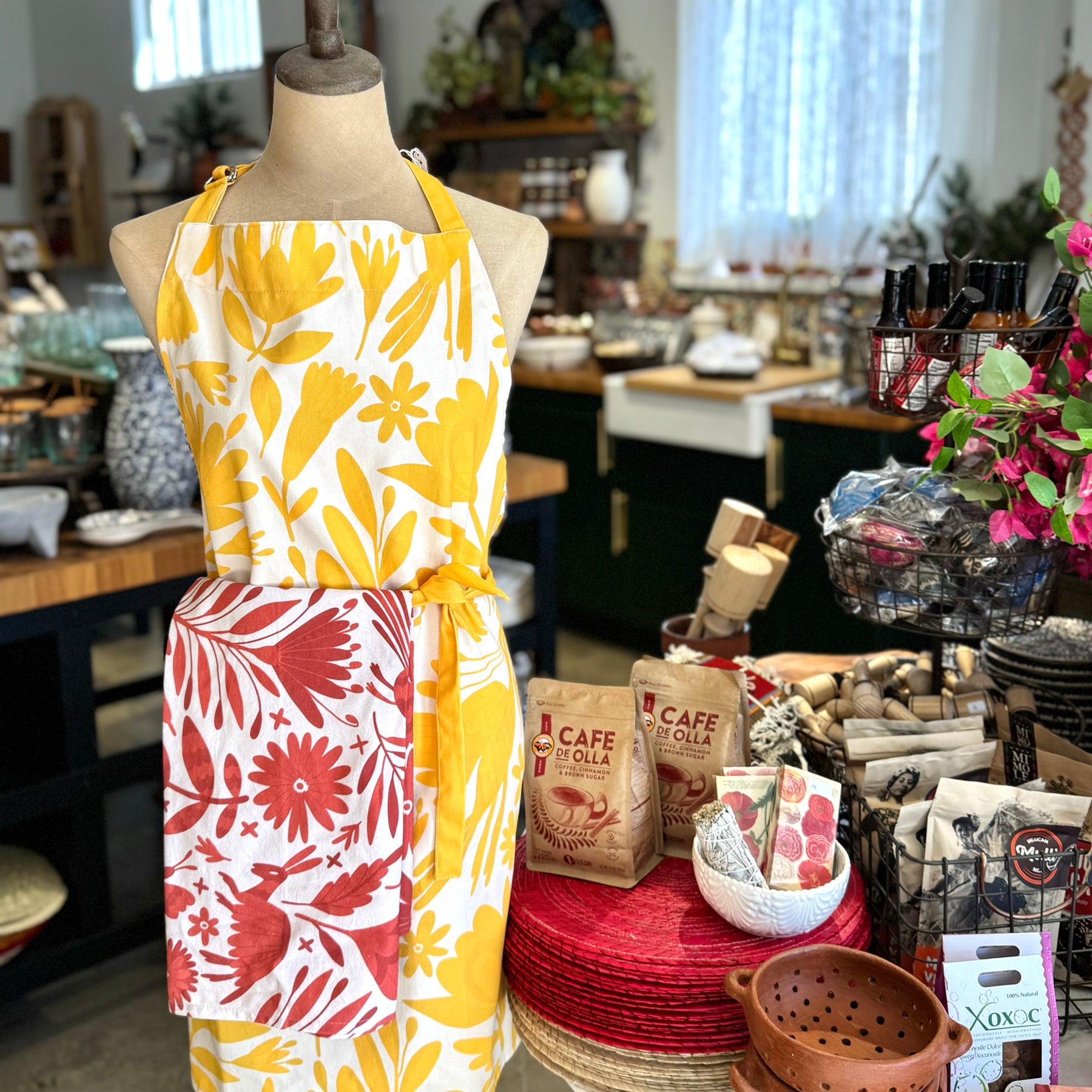 photo of yellow otomi apron with yellow straps displayed on a mannequin with kitchenwares background.