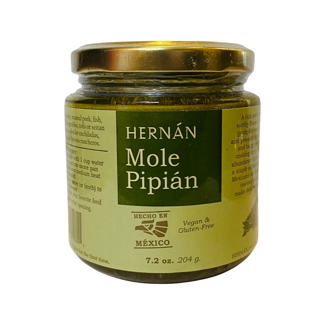 Front view of Hernán Mole Pipian in clear glass branded jar with gold colored lid