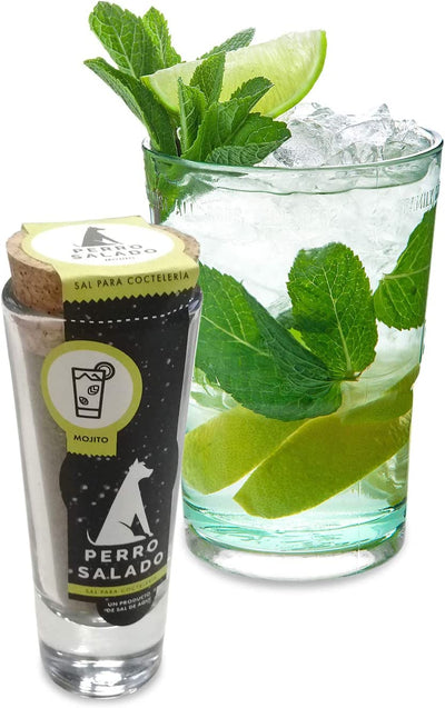 Front view of Mojito Salt in clear glass branded jar with cork lid sitting adjacent to a mojito cocktail in a clear glass