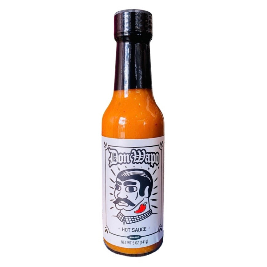 Front view of a glass bottle containing 5 oz of hot sauce. The label is a white and features a graphic of a man with slicked back black hair, giant black eyebrows, a black mustache, and a red chili pepper tattoo on his neck. 