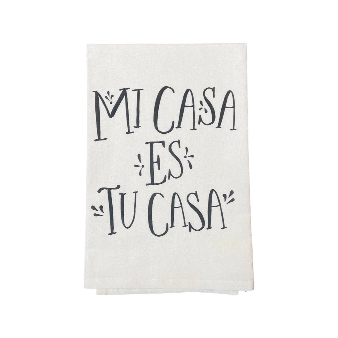folded off white cotton towel with printed graphic reading "Mi Casa Es Tu Casa"
