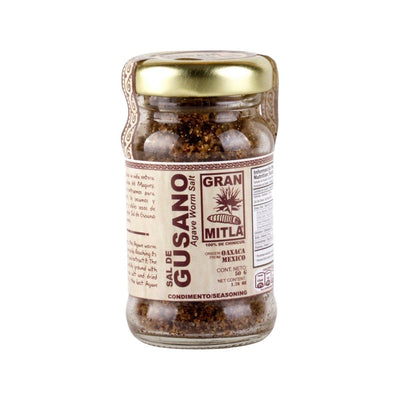 front view of Sal De Gusano (Agave Worm Salt, 100% Chinicuil) - Small in clear glass branded packaging with gold colored lid