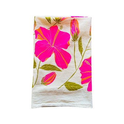 Folded hibiscus tea towel features graphic of pink hibiscus flowers with green stems