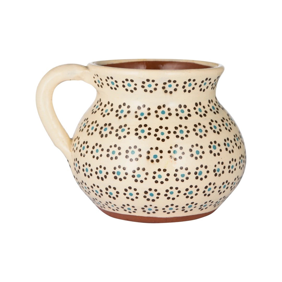 side angle of cream colored mug with painted dots resembling the shape of a flower