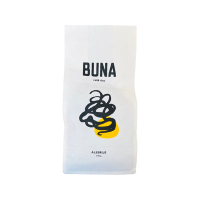 A single white 340 gram bag of Buna Coffee that features abstract art of black lines and a yellow spot on the center of the bag.