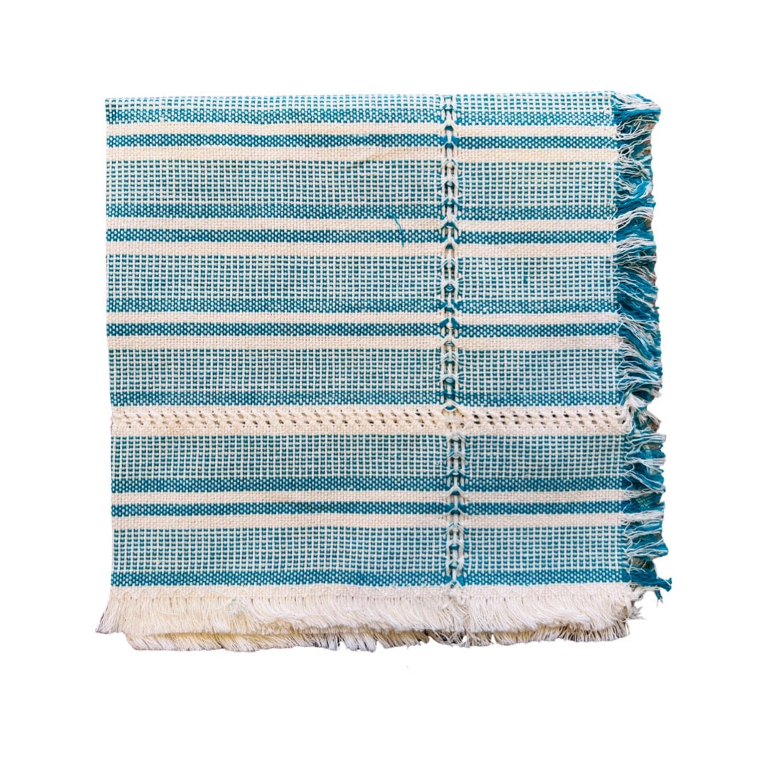 handwoven teal and natural striped napkin folded in quarter.